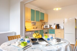A modern kitchen with a dining area, featuring a table set for two, a microwave, and a refrigerator.