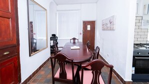 A conference room with a wooden table and chairs, a large mirror, and a door leading to a kitchen area.