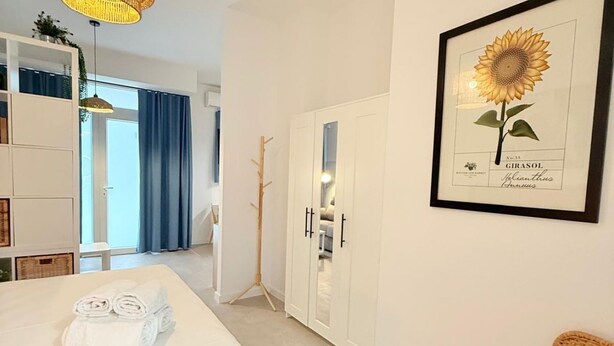 Une chambre d’hôtel avec un lit, une œuvre d’art représentant un tournesol encadré, une armoire et une vue sur l’extérieur.