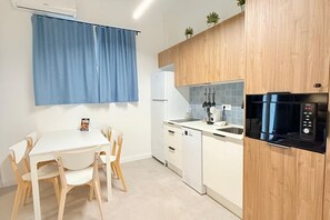 A compact kitchen with a white countertop, a black microwave, a white dishwasher, and wooden cabinets. -  Oceanografic Suite 1 (València)