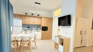 Une cuisine moderne avec des meubles en bois, un four à micro-ondes encastré et un coin repas comprenant une table et des chaises blanches.