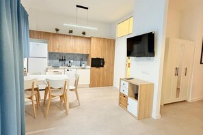 A modern kitchen with wooden cabinets, a built-in microwave, and a dining area with a white table and chairs. -  Oceanografic Suite 1 (València)