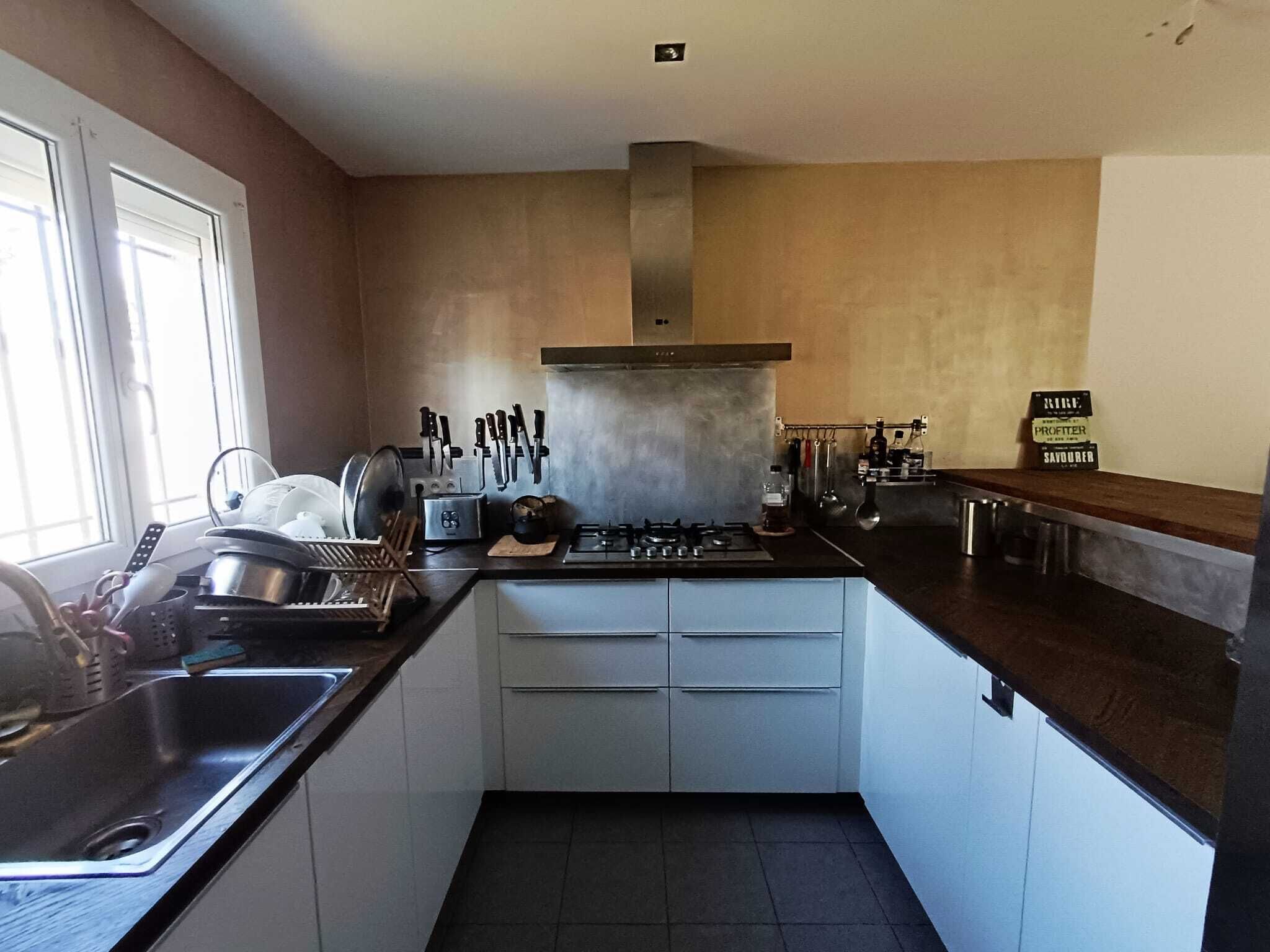 Een kleine keuken met een gasfornuis, spoelbak en witte keukenkastjes.