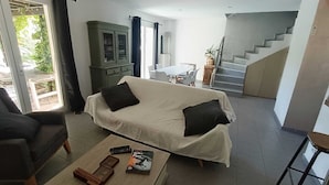 A modern living room with a sofa, coffee table, and a cabinet. There is a staircase leading to another level. - Villa Grape Bubble (L'Isle-sur-la-Sorgue)