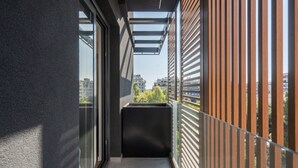 A narrow balcony with a glass door and a view of buildings in the distance. - LIV Athinum 1 - Luxury Apartment 3A (Athens)