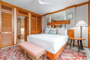 Ein Hotelzimmer mit einem großen Bett, einem Nachttisch, einer Bank, einem Spiegel und Holzwandverkleidung.