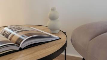 Uma mesinha de madeira redonda com um livro e um vaso branco.
