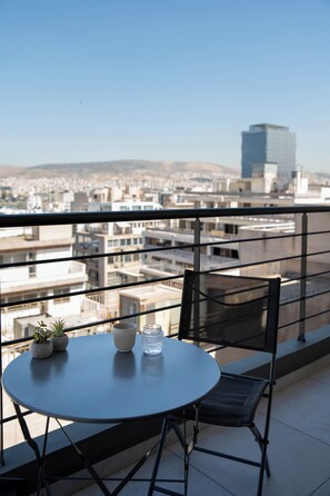 A balcony with a round table, two chairs, and a small potted plant. - Nuvia UrbanStay Piraeus Apartments (Piraeus)