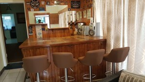 A bar area with wooden paneling, a mirror, and three bar stools.