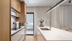 Una cocina moderna con armarios de madera, encimera blanca y lavamanos integrado.