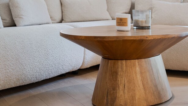 Una sala de estar moderna con una mesa de centro de madera, un sofá blanco y un vaso de agua.