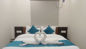 A neatly made bed with white bedding and blue accents, including pillows and a blanket. - Hotel Kingston (Ranchi)