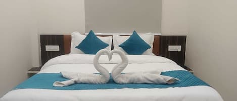 A neatly made bed with white bedding and blue accents, including pillows and a blanket.