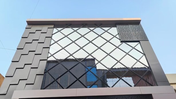 A building with a modern architectural design, featuring a prominent geometric pattern on the facade and a large window with a diamond grid. - Hotel Kingston (Ranchi)