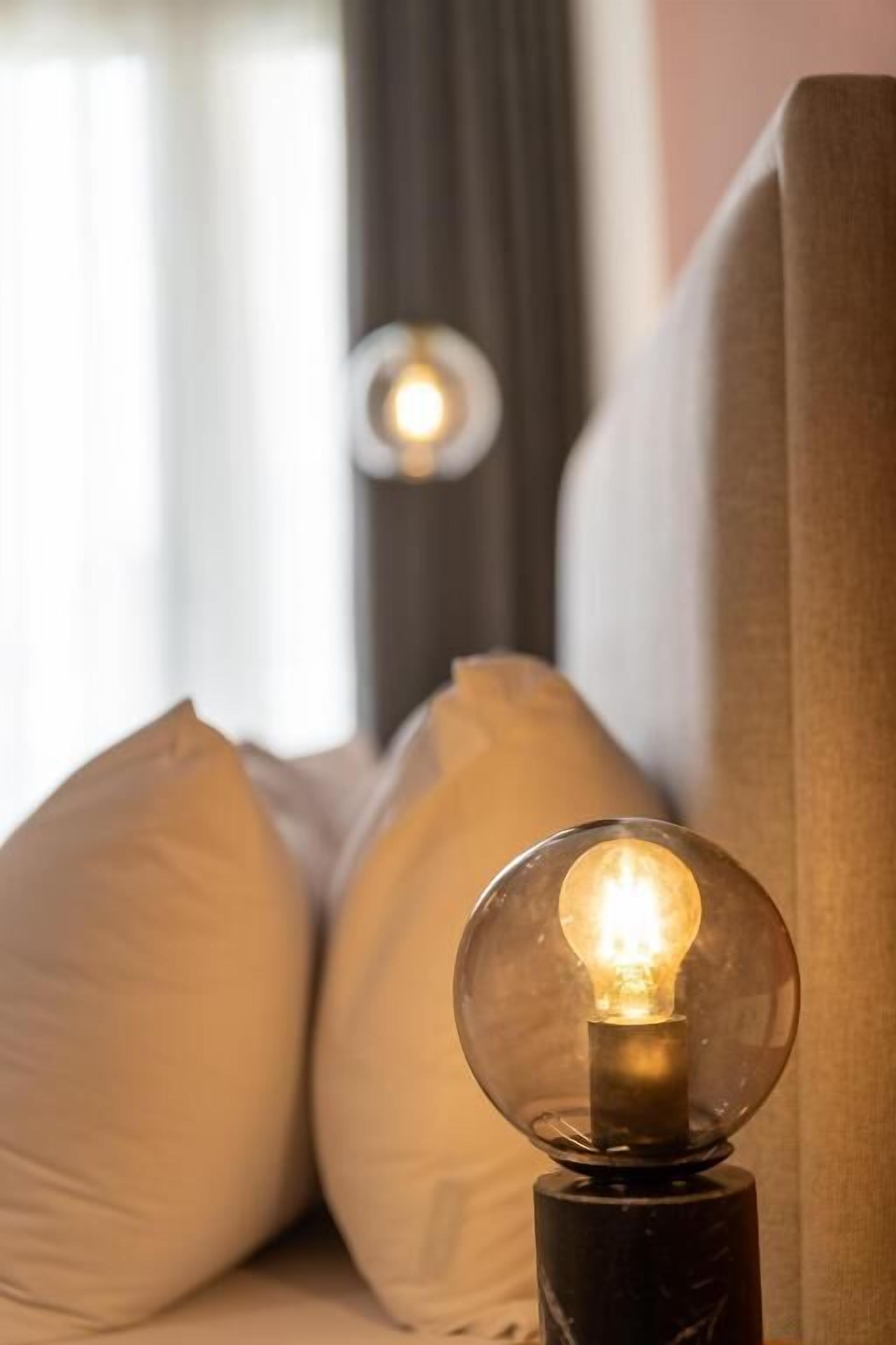 Eine Lampe mit Glaskuppel und sichtbarer Glühbirne, auf einem schwarzen Sockel platziert.
