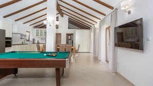 Une pièce spacieuse comprenant une table de billard, un coin repas et une cuisine.