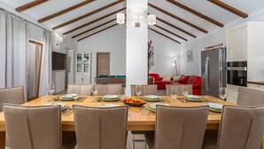 Un espace repas avec une table en bois dressée pour six personnes, entourée de chaises.