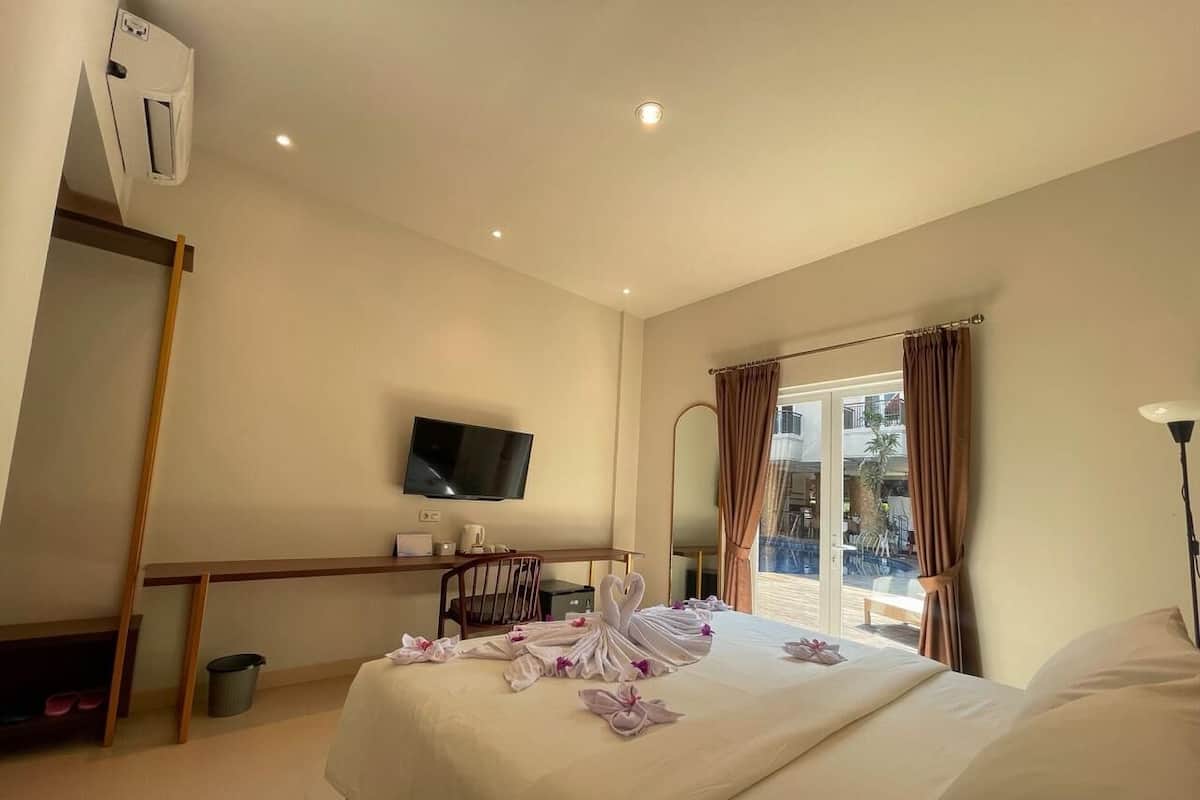A hotel room with a bed, a desk, a television, and a view of the outdoors.