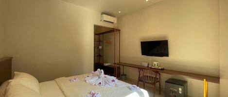 Una habitación de hotel con una cama, un escritorio, un televisor y un equipo de aire acondicionado.