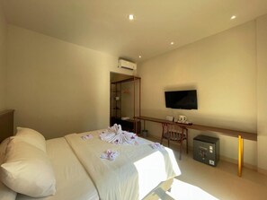 Una habitación de hotel con una cama, un escritorio, un televisor y un equipo de aire acondicionado.