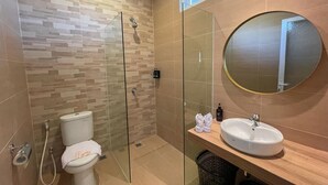 Une salle de bain moderne avec une douche à parois de verre, des toilettes, un lavabo avec un miroir et une fenêtre au-dessus du lavabo.
