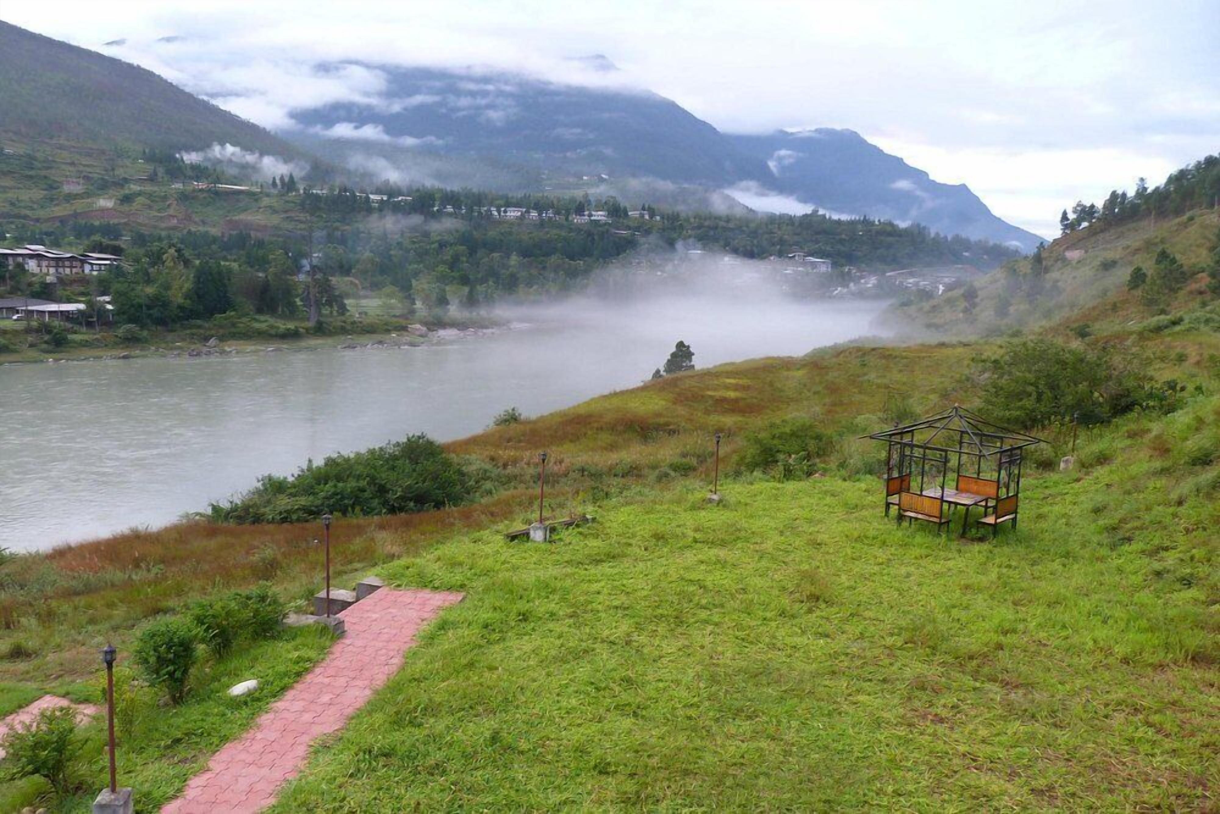 A riverside view with a gazebo and a paved path.