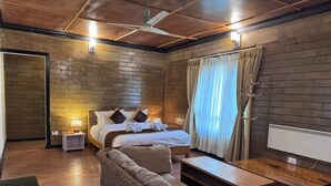 A room with a bed, a sofa, a small table, a nightstand, and a ceiling fan.