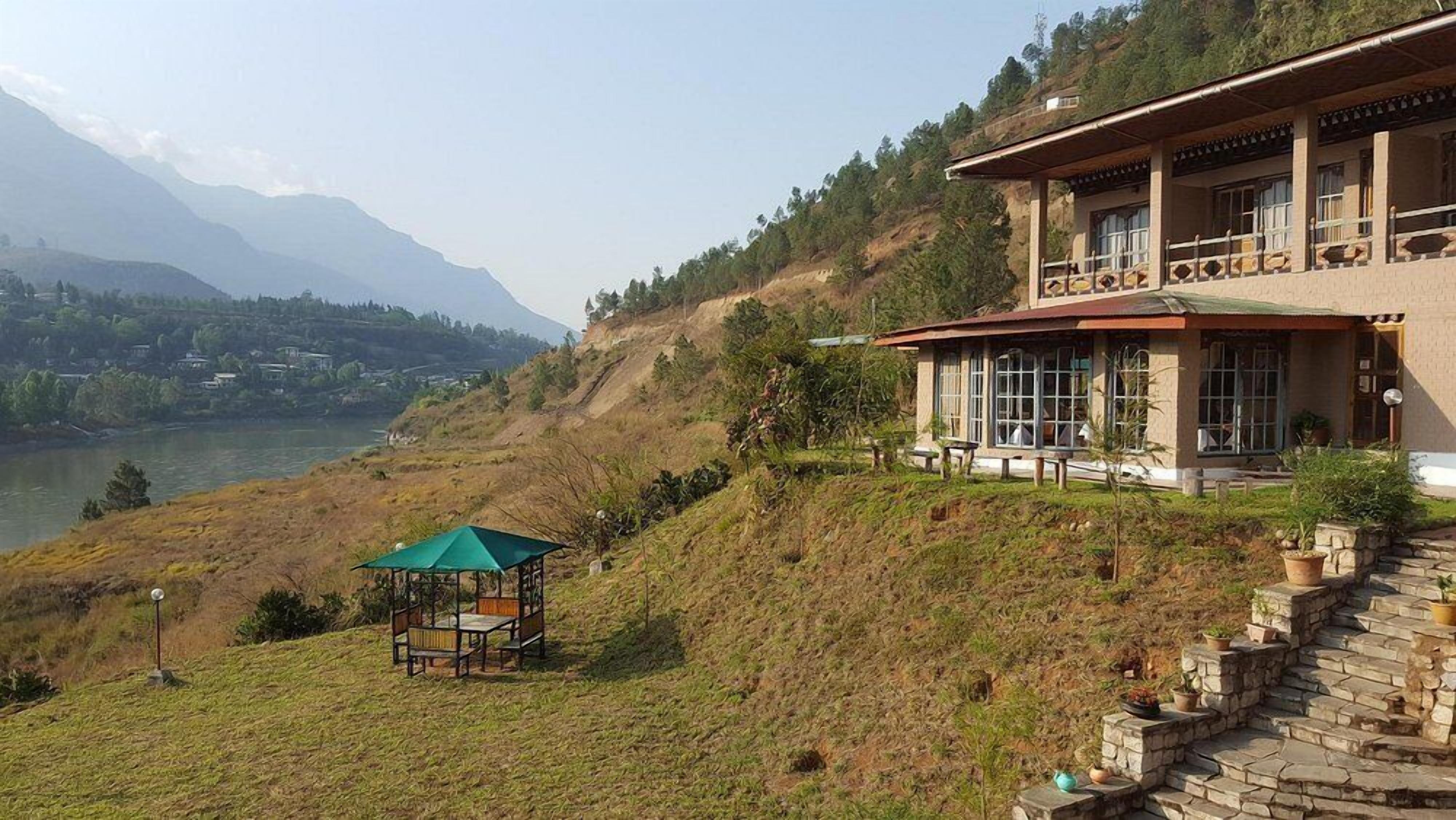 A two-story building with large windows, a balcony, and a view of a lake and mountains.