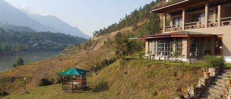 A two-story building with large windows, a balcony, and a view of a lake and mountains.