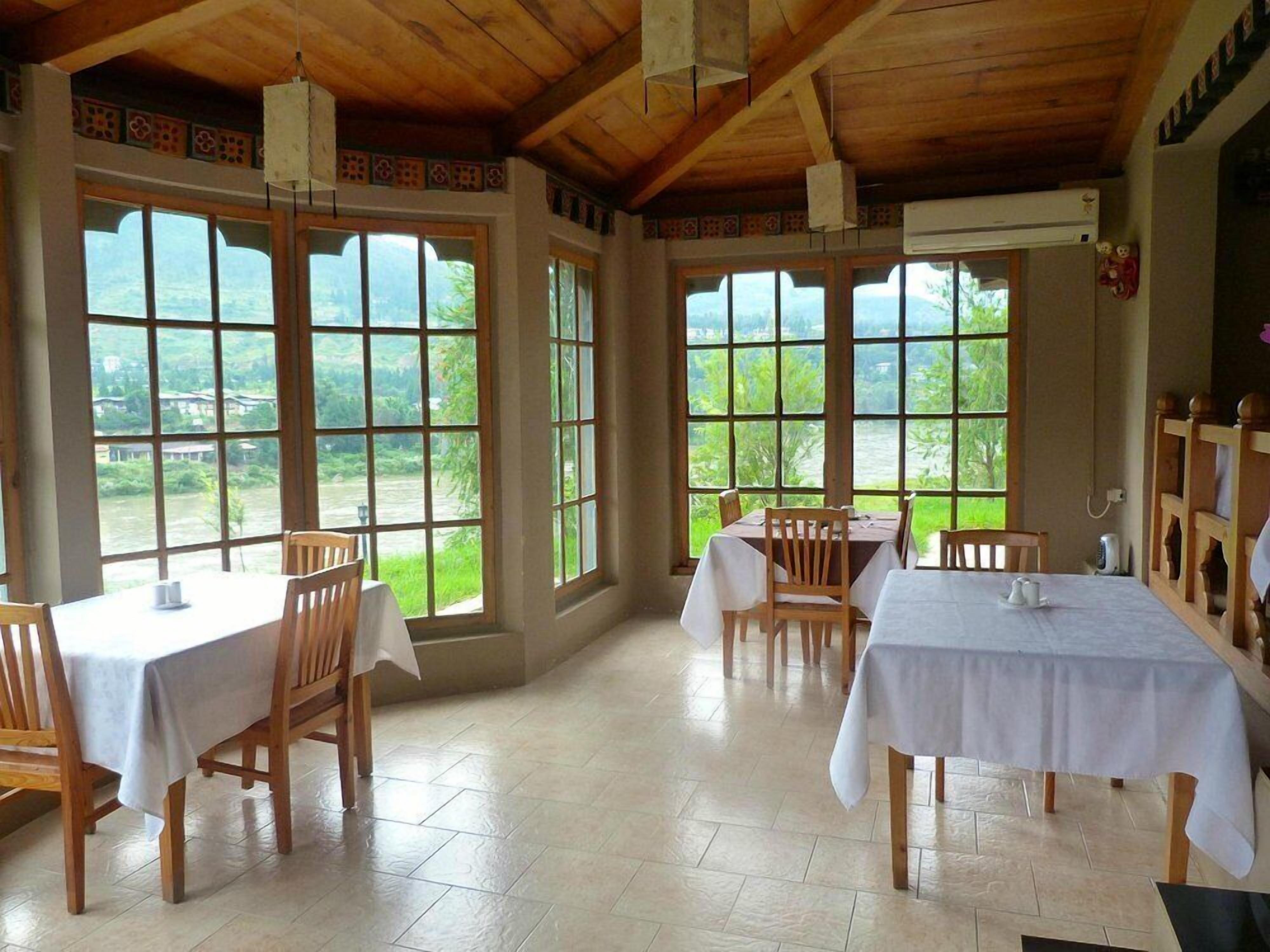 Comedor con ventanas amplias, mesas y sillas de madera.