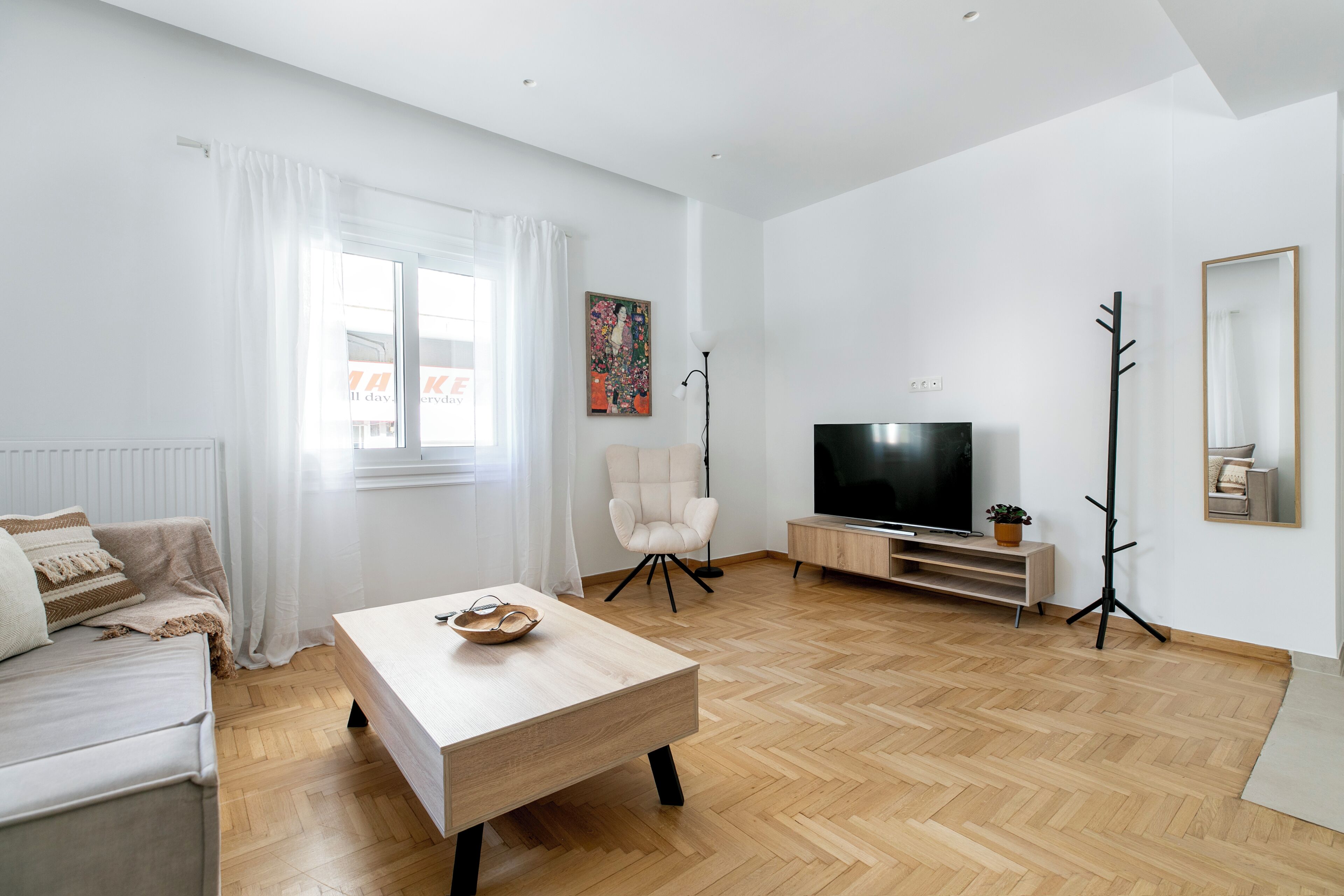 Una sala de estar moderna con un sofá, una mesa de centro, un televisor y un cuadro en la pared.