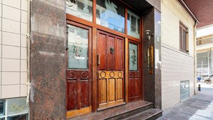 A building with a large wooden door, a stone facade, and a small set of steps leading up to the entrance. - Anatoli - Athenian 2-BR Apartment in Athens (Zografos)