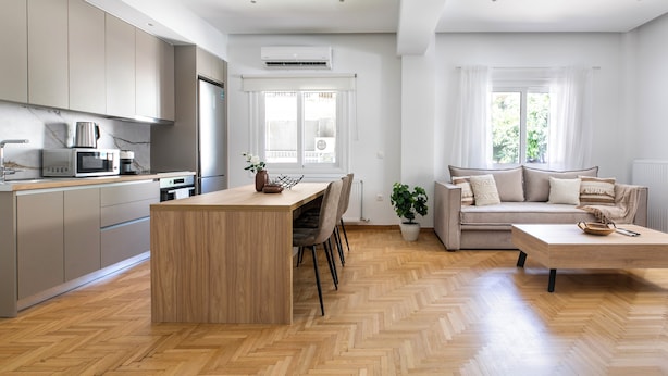 A modern kitchen with built-in appliances, a dining area with a wooden table and chairs, and a living room with a sofa and a coffee table. - Anatoli - Athenian 2-BR Apartment in Athens (Zografos)