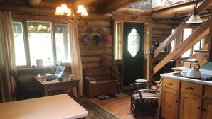 Un interior de cabaña acogedor, con un escritorio de madera, una computadora portátil y un comedor con un hervidor.