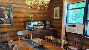 Un comedor de madera con una mesa larga, sillas, una araña y un ventanal con vistas.