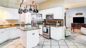 A modern kitchen with white cabinets, stainless steel appliances, and a granite countertop. - Outdoor Oasis: Group Getaway in Pensacola! (Pensacola)
