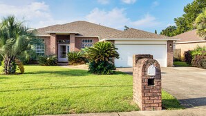 A two-story house with a garage, a brick mailbox, and well-maintained lawn. - Outdoor Oasis: Group Getaway in Pensacola! (Pensacola)