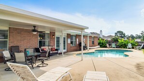 A covered patio with a pool, lounge chairs, and outdoor furniture. - Outdoor Oasis: Group Getaway in Pensacola! (Pensacola)