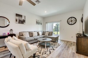 A modern living room with a sectional sofa, a round coffee table, and a white armchair.