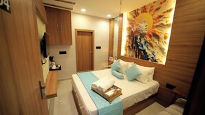 A modern bedroom with a large bed, a bedside table, a mirror, and a wall art piece. - Staykart Boutique Hotel  (Bhilwara)