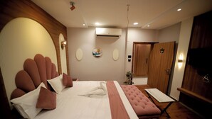 A hotel room with a large bed, a small sofa, a wooden wardrobe, and a television. - Staykart Boutique Hotel  (Bhilwara)