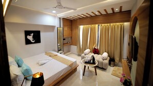 A modern hotel room with a bed, bedside table, and a seating area with a sofa and armchairs. - Staykart Boutique Hotel  (Bhilwara)