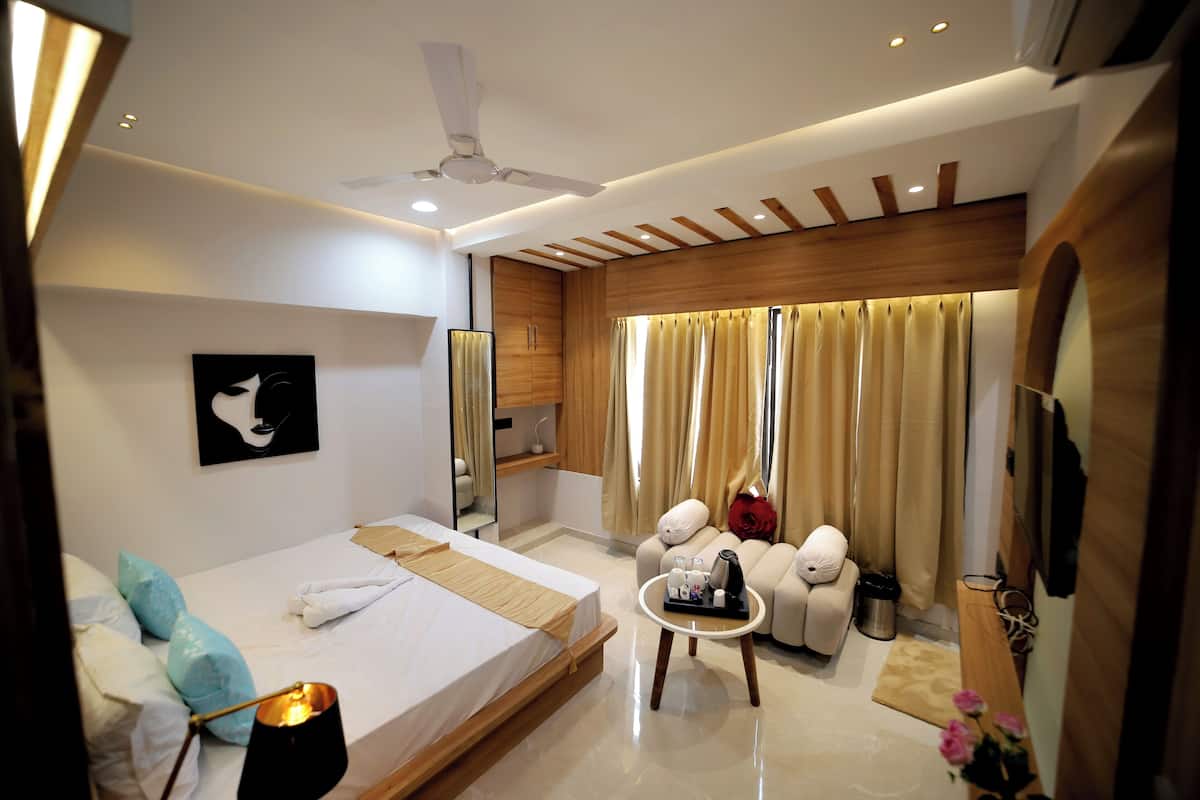 Una habitación de hotel moderna con cama, mesita de noche y zona de estar con sofá y sillones.