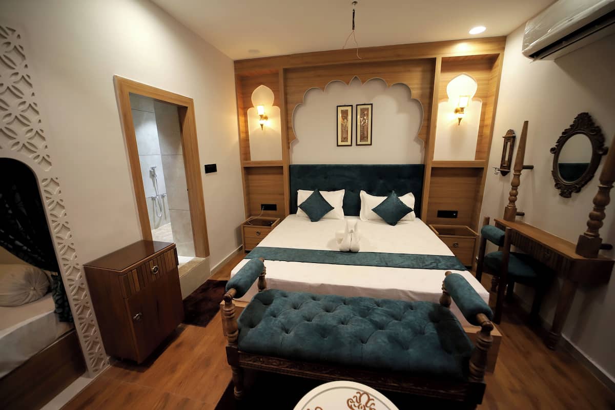 Un dormitorio con una cama grande, una mesita de noche de madera, un banco y un espejo en la pared.