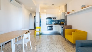A modern kitchen with white cabinets, a microwave, and a stove. There is a dining area with a wooden table and chairs.