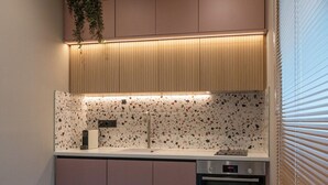 A modern kitchen with a built-in oven, a countertop with a speckled backsplash, and a wooden ceiling with recessed lighting. - Latitude 37 (Kalamata)