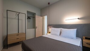 A modern bedroom with a bed, bedside tables, a wardrobe, and a hanging light fixture. - Latitude 37 (Kalamata)