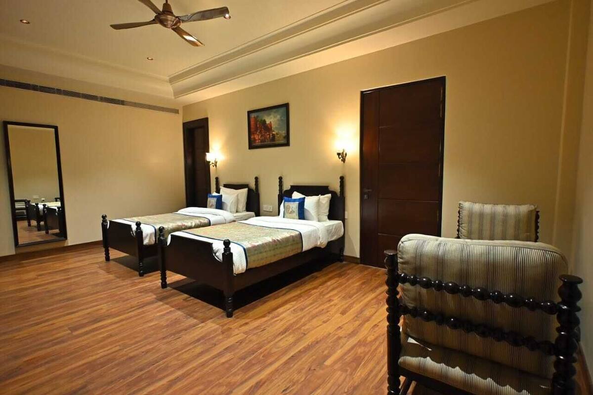 A hotel room with a large bed, a chair, a ceiling fan, and a painting on the wall.