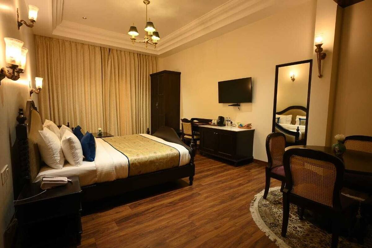 A hotel room with a bed, a dresser, a television, and a mirror.