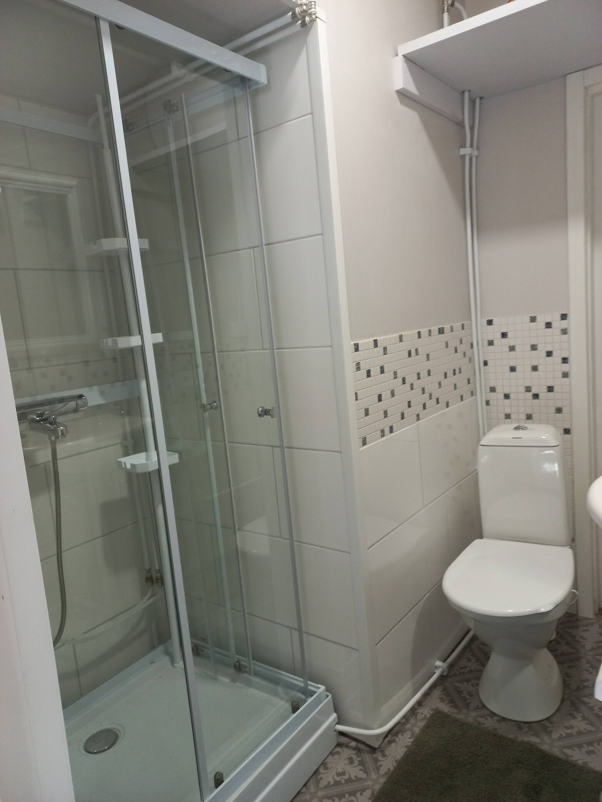 Une salle de bain avec une douche à parois de verre, des toilettes et un lavabo.